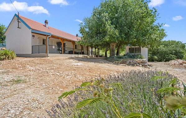 A house with a red roof, a covered porch, and a garden with lavender plants. - Gorgeous home in Razvode (Razvode)