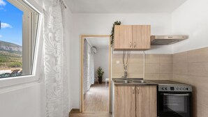 Una cocina compacta con horno integrado, pileta de acero inoxidable y alacenas de madera.