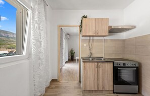 A compact kitchen with a built-in oven, a stainless steel sink, and wooden cabinets. - Gorgeous home in Razvode (Razvode)
