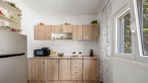 Cocina compacta con armarios de madera, microondas y ventana con vistas a zonas verdes.