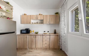 A compact kitchen with wooden cabinets, a microwave, and a window with a view of greenery. - Gorgeous home in Razvode (Razvode)