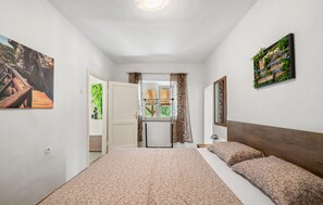A bedroom with a bed, a window, and a door leading to a bathroom. - Gorgeous home in Razvode (Razvode)