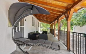 A covered outdoor seating area with a cushioned lounge chair, a table, and a bench. - Gorgeous home in Razvode (Razvode)