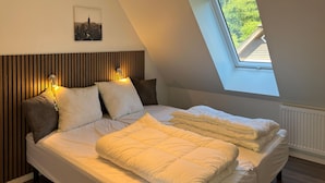 A bedroom with a sloped ceiling, a skylight, a bed with white bedding, and a cityscape picture on the wall. - Stunning home in Hobro with WiFi (Hobro)