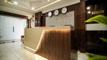 A reception desk with a wooden finish, a clock, and a 'PANTRY' sign.
