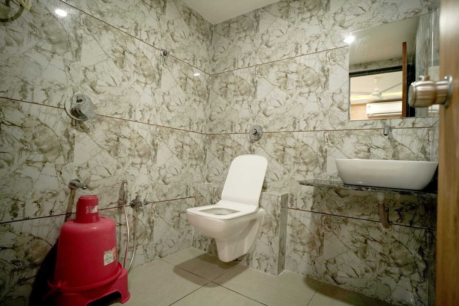 A bathroom with a toilet, a sink, and a marble wall.
