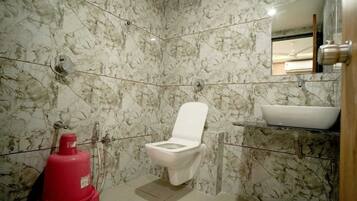 A bathroom with a toilet, a sink, and a marble wall.