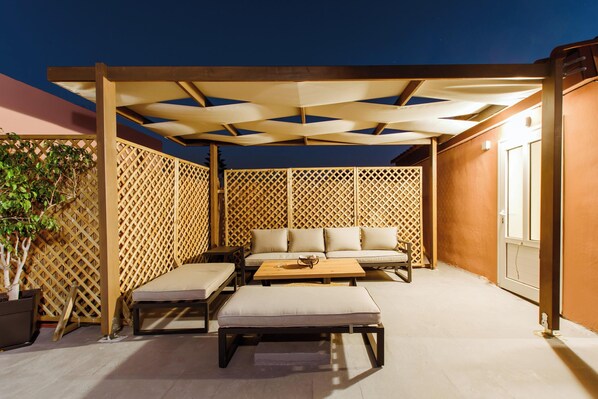 A covered outdoor seating area with a sofa, two armchairs, and a coffee table. - Krinis Home (Chania)