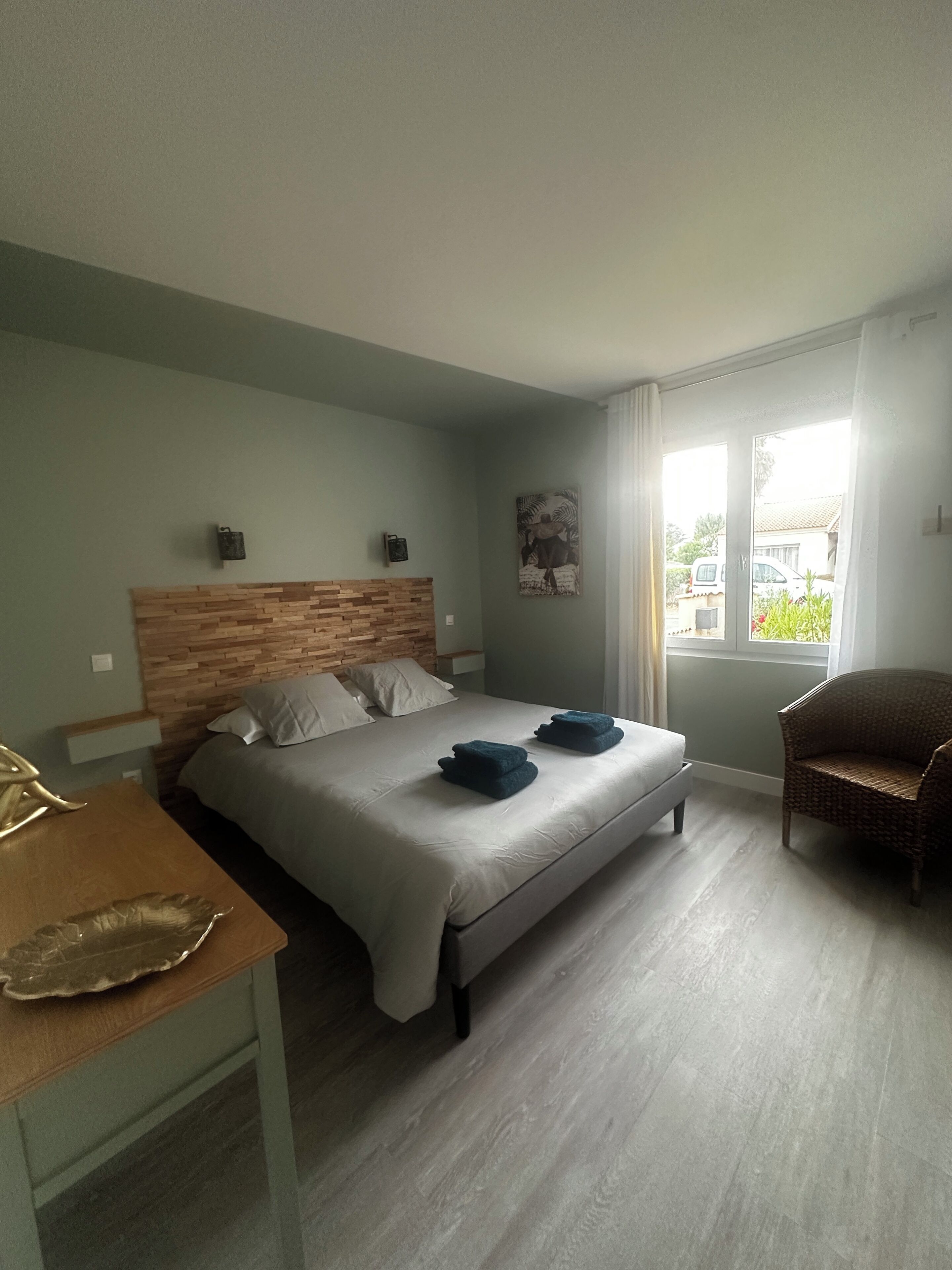 Ein Schlafzimmer mit einem Bett, einem Sessel, einem Tisch und einem Fenster.