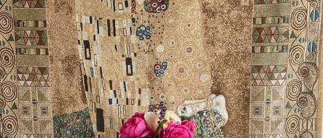 Una mesa con un florero y un vaso de agua, frente a una pared con un mosaico.