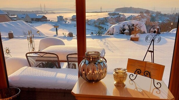 A cozy room with a fireplace, a view of a snowy landscape, and a table with decorative items.