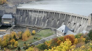 A large dam with a control building and a small structure near the water.