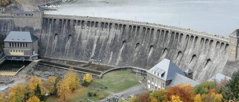 A large dam with a control building and a small structure near the water.