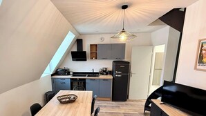 Een moderne keuken met een ingebouwde oven, een zwarte koelkast en een eethoek met een houten tafel en stoelen.