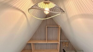 Een modern interieur met een schuine plafond, een hanglamp en houten planken.