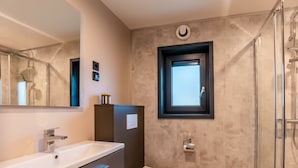 A modern bathroom with a large mirror, a white sink, a toilet, and a shower enclosure. - Wulfenia Waterfront 6 (Ossiach)