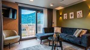 A modern living room with a sofa, armchair, and a small table with a plant. - Wulfenia Waterfront 6 (Ossiach)