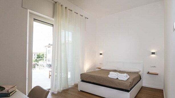 A bedroom with a bed, a desk, a chair, and a view through a door. - My Holiday Olbia Rooms & Lounge Room 4 by Rentbeat (Olbia)