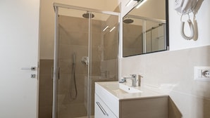 A modern bathroom with a glass-enclosed shower, a white sink, and a mirror above the vanity. - My Holiday Olbia Rooms & Lounge Room 4 by Rentbeat (Olbia)