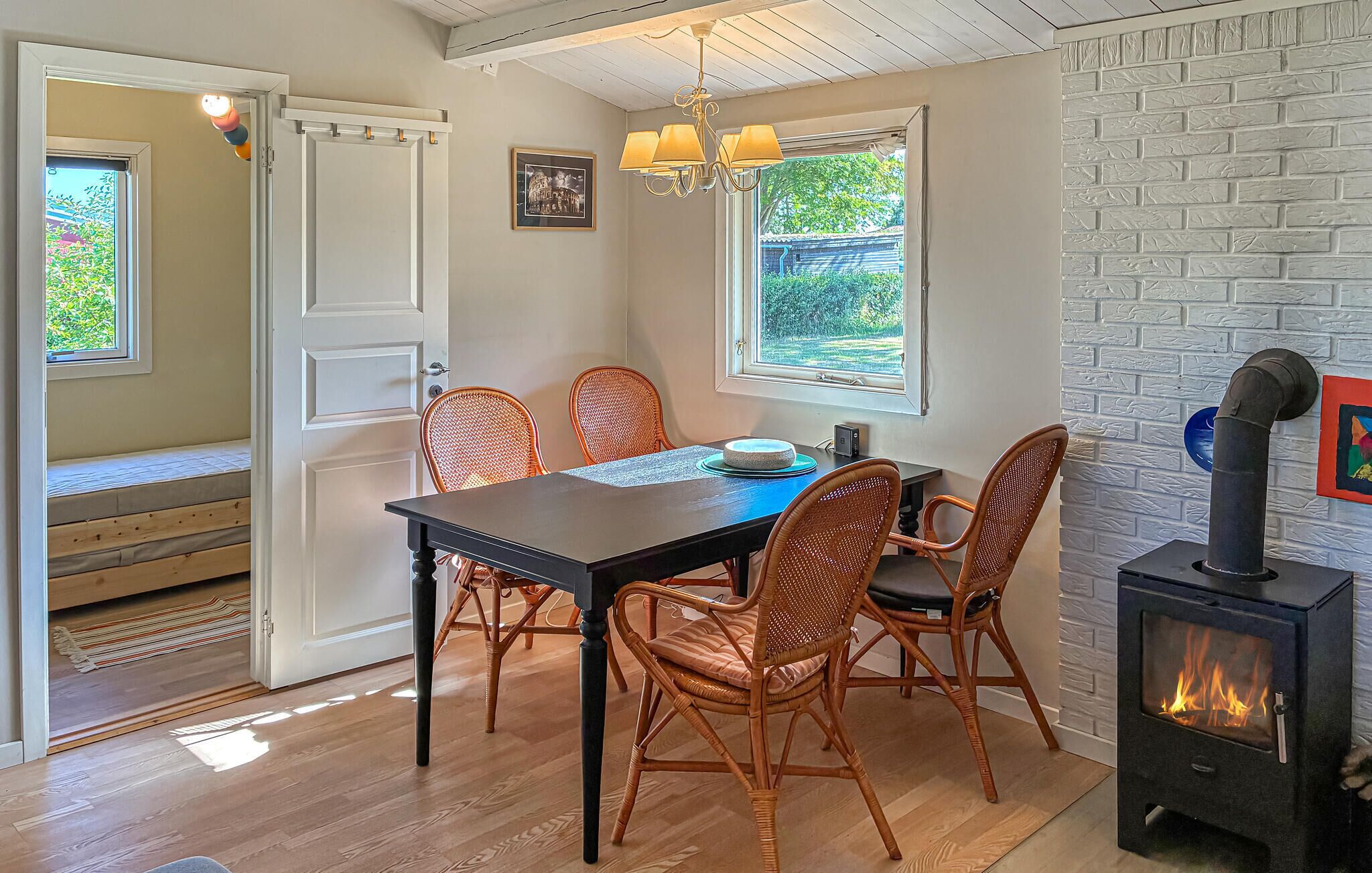 A dining area with a table, chairs, a chandelier, a fireplace, and a view through the window.