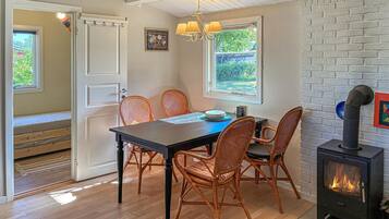 A dining area with a table, chairs, a chandelier, a fireplace, and a view through the window.