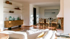 A spacious living area with a wooden console, wicker chairs, a white sofa, and a bookshelf with pottery. - VILLA CANADELL (Palafrugell)