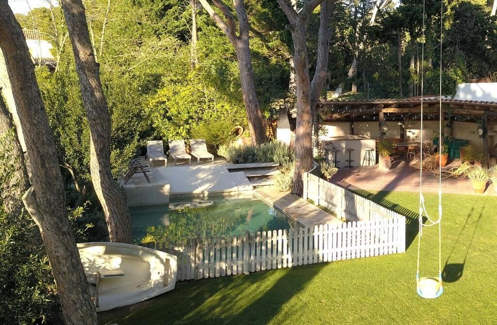 A backyard with a swimming pool, lounge chairs, a deck, and a pergola.