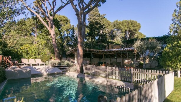 A swimming pool with a wooden fence, lounge chairs, and a pergola structure. - VILLA CANADELL (Palafrugell)