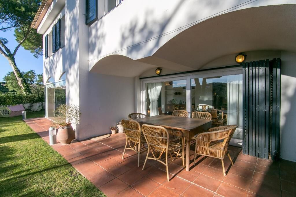 A patio with a dining table and chairs, a sliding glass door, and a potted plant.