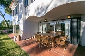 Een terras met een eettafel en stoelen, een schuifpui en een potplant.