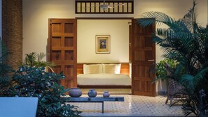 A room with a bed, wooden doors, a ceiling fan, a framed picture, and potted plants. - Beautiful Khmer house with pool at the edge of the Angkor conservation zone (ក្រុងសៀមរាប)