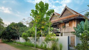 A traditional wooden house with a balcony, surrounded by lush greenery and a clear sky. - Beautiful Khmer house with pool at the edge of the Angkor conservation zone (ក្រុងសៀមរាប)