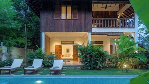 A two-story house with a pool, lounge chairs, and a well-maintained garden. - Beautiful Khmer house with pool at the edge of the Angkor conservation zone (ក្រុងសៀមរាប)