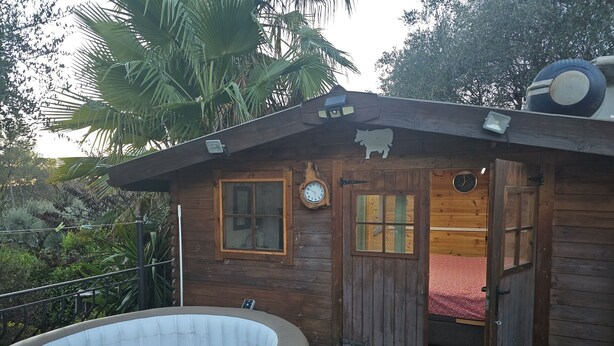 Una cabaña de madera con hidromasaje, un reloj y una cama.