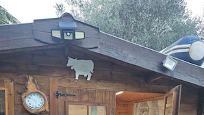 Una cabaña de madera con una cama, un reloj y una cabeza de vaca decorativa.