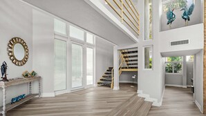 Tilava sisätila, jossa on portaikko, suuret ikkunat ja koristeellinen peili.