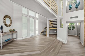 Ein geräumiges Interieur mit Treppe, großen Fenstern und einem dekorativen Spiegel.