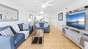 Ein modernes Wohnzimmer mit Sofa, Couchtisch, Fernseher und Deckenventilator.