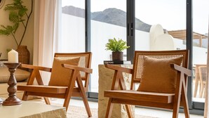 Two wooden chairs with woven backs, a book titled 'TOM FORD,' a potted plant, and a candle on a table.