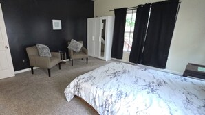 A bedroom with a bed, two armchairs, a wardrobe, and a door. - 3 BR house (sleeps 8 adults) 8 minutes from Atlanta stadium & downtown (Atlanta)