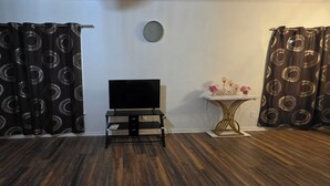 A room with a flat-screen TV on a black stand, a small white table with a vase, and two curtains with circular patterns. - 3 BR house (sleeps 8 adults) 8 minutes from Atlanta stadium & downtown (Atlanta)