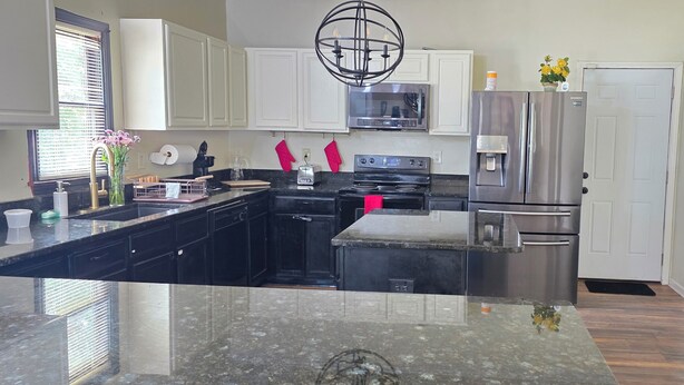 A kitchen with white cabinets, a stainless steel refrigerator, a microwave, and a black stove. - 3 BR house (sleeps 8 adults) 8 minutes from Atlanta stadium & downtown (Atlanta)