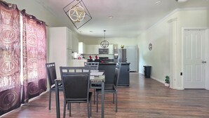 A dining area with a table and chairs, a kitchen in the background, and a door to the right. - 3 BR house (sleeps 8 adults) 8 minutes from Atlanta stadium & downtown (Atlanta)