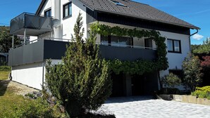 Una moderna casa a due piani con un balcone, un'antenna parabolica e un vialetto lastricato.