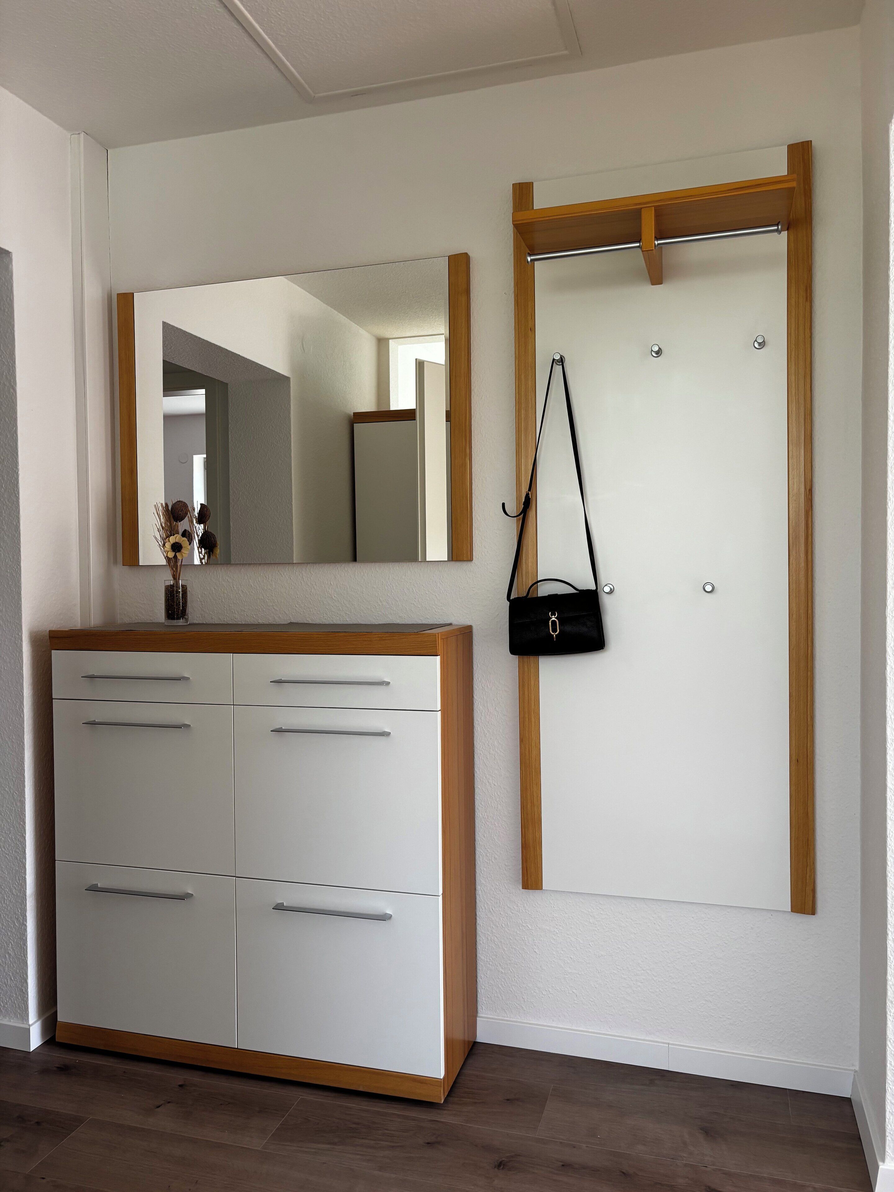 A room with a white wardrobe, a mirror, and a door with a wooden frame.
