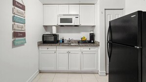 A kitchen with white cabinets, a microwave, a toaster, a coffee maker, and a refrigerator. - Cozy Apt, King Bed + Huge TV, Near TPA & Stadium (Tampa)