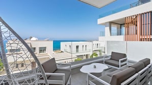 Ein Balkon mit Sitzgelegenheit, freier Meerblick und moderner Architektur.