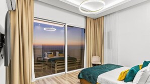 Ein Hotelzimmer mit Bett, Stuhl, Tisch und einer großen Schiebeglasdoor zum Außenbereich.