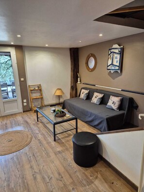 Un salon moderne avec un canapé, une table basse en verre, une lampe et un plancher en bois.