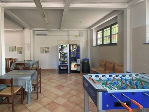 Ein Raum mit Tischfußball, einem Verkaufsautomaten und einem Tisch mit Stühlen.